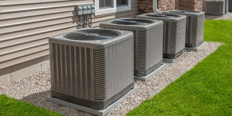 Row of new central air conditioner condensers on a gravel pad after AC replacement in Provo, UT